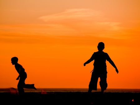 Kids having fun on the beach playing footballの写真素材
