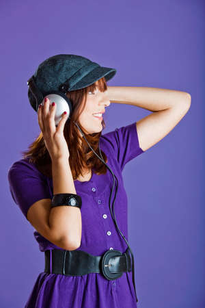 Beautiful and happy young woman listen music with headphones, over a violet backgroundの写真素材