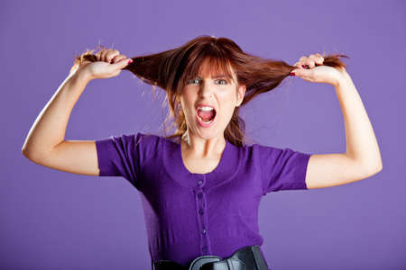 Beautiful woman with a angry expression pulling her hairの写真素材