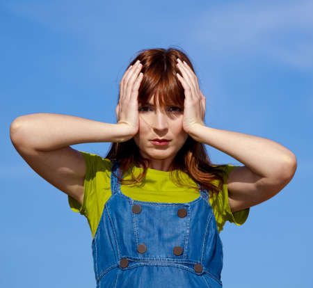 Portrait of a young woman over a blue sky with a worried expressionの写真素材
