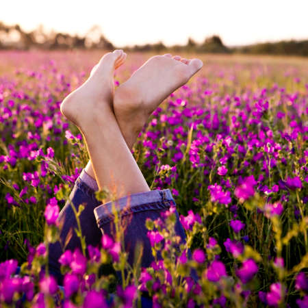 Female crossed legs on a beautiful flowery meadowの写真素材