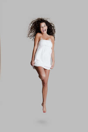 Beautiful and happy young woman jumping over a grey backgroundの写真素材