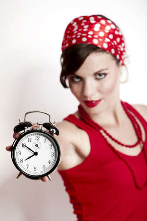 Beautiful and fashion young woman with a pin-up look holding a clockの写真素材