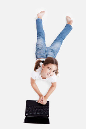 Top view of a little girl lying on floor working with a laptopの写真素材