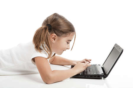 Little girl lying on floor working with a laptop