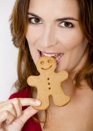 Close-up portrait of a beautiful young woman bitting a gingerbread cookieの写真素材