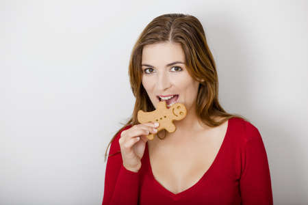 Beautiful young woman bitting a gingerbread cookieの写真素材