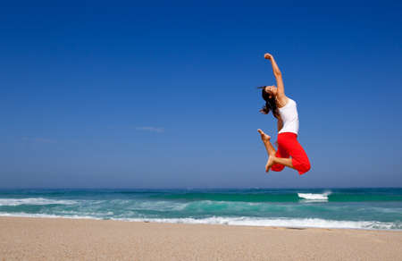 Beautiful young woman jumping on  the beachの写真素材