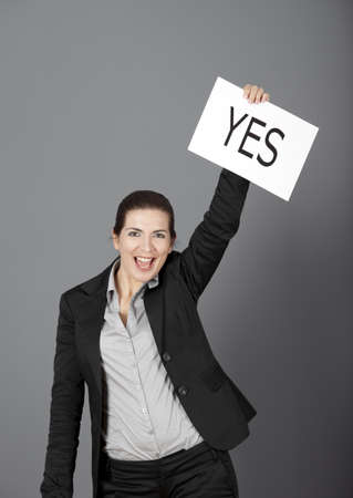 Business young woman showing a paper card with the word YESの写真素材