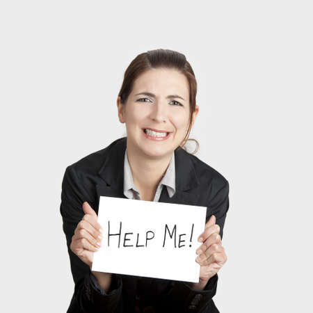 Stressed business woman imploring for help, holding a cardboard with the message "Help"の写真素材