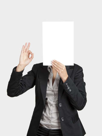 Confident woman showing a blank paper sheet in front of her headの写真素材
