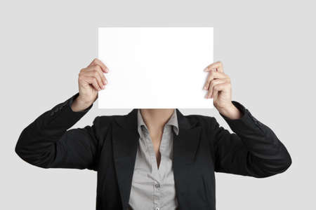 Woman showing a blank paper sheet in front of her headの写真素材