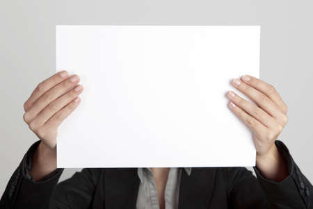 Woman showing a blank paper sheet in front of her headの写真素材