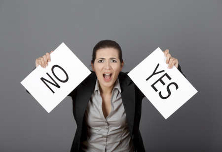 Business young woman trying to make a decision between Yes or No choice, over a gray backgroundの写真素材