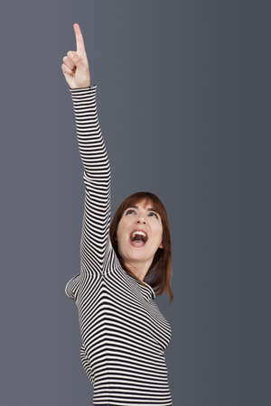Portrait of a successful young woman with arm up over a grey background
の写真素材