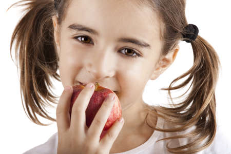 Portrait of a beautiful little girl eating a red appleの写真素材
