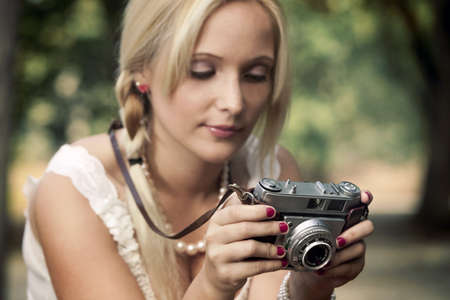 Beautiful young girl taking pictures with a old vintage camera
