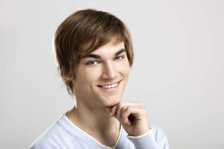 Portrait of a handsome and happy young man thinking, over a gray background