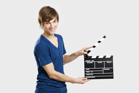 Casual young man holding a clapboard, over a gray backgroundの写真素材