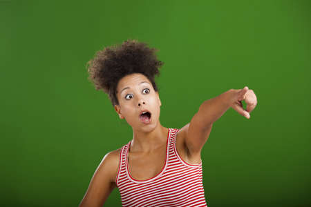 African woman astonished with something and pointing, over a green backgroundの写真素材