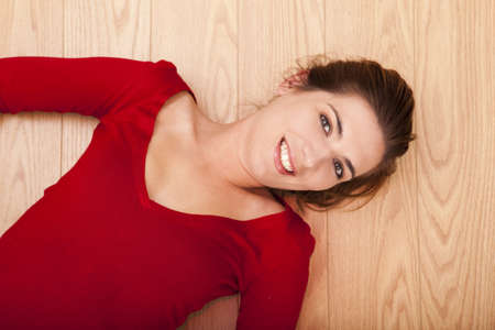 Beautiful woman lying on the floor and smiling to the cameraの写真素材