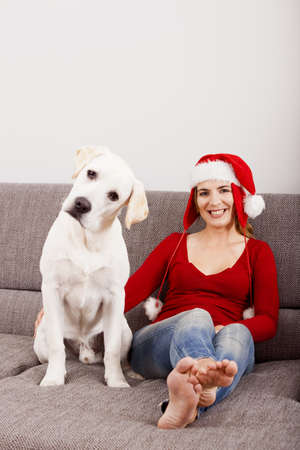 Woman sitting on the sofa with her dog and wearing a santa hat  の写真素材