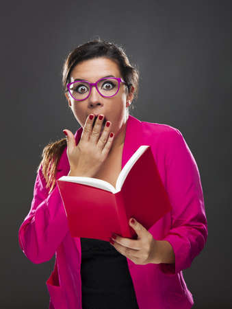 Middle aged woman with a astonished expression and holding a red book