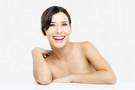 Beautiful and happy asian woman with arms over a white table