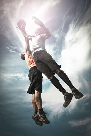 Two Basketball players playing street basket and jumping together to catch the ball Two Basketball players playing street basket and jumping together to catch the ball
