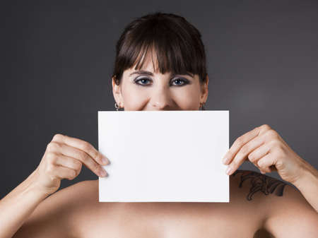 Beautiful woman holding a white billboard in front of the faceの写真素材