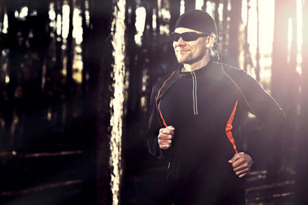 Athletic man doing exercise, running in the forestの写真素材