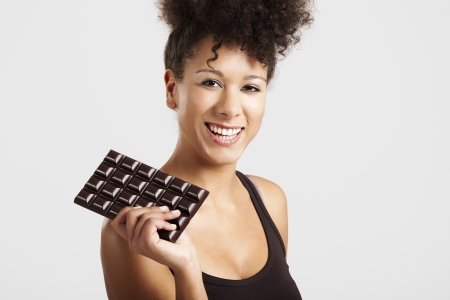 Beautiful african woman holding a huge dark chocolate barの写真素材