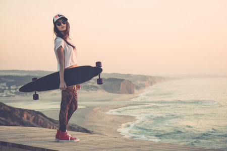 Beautiful and fashion young woman posing with a skateboardの写真素材