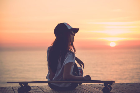 Beautiful and fashion young woman posing with a skateboardの写真素材