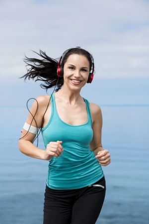 Beautiful young woman jogging on a boardwalk and listen musicの写真素材