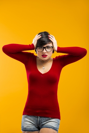 Nerd girl angry with something, aganist a yellow backgroundの写真素材