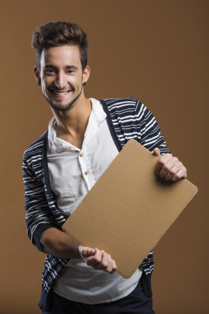 Handsome young man smiling and holding a card boardの写真素材