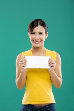 Beautiful asian woman holding a white paper card, over a green backgroundの写真素材