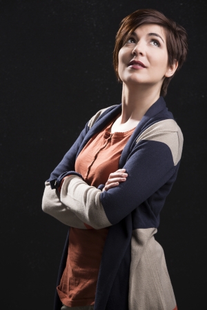 Beautiful woman with a modern hair cut and thinking, standing over a dark backgroundの写真素材
