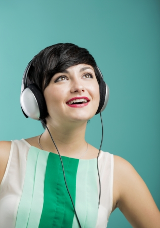 Beautiful and fashion woman listen music with headphones aganist a blue backgroundの写真素材