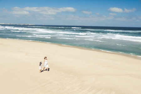 Beautiful woman and her little daughter walking on the beachの写真素材