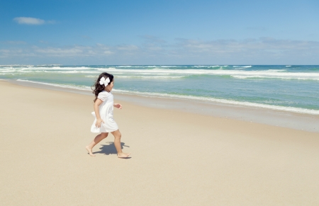 Little girl walking on the beach with a white dressの写真素材
