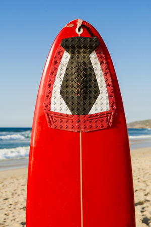 Red surfboard on the sand on a very beautiful sunny dayの写真素材