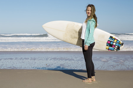 Tenage girl in the beach with her surfboard