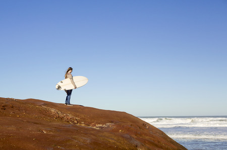 Teenage girl over the rocks checking the waves
