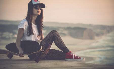 Beautiful fashion skater girl posing with  a skate boardの写真素材