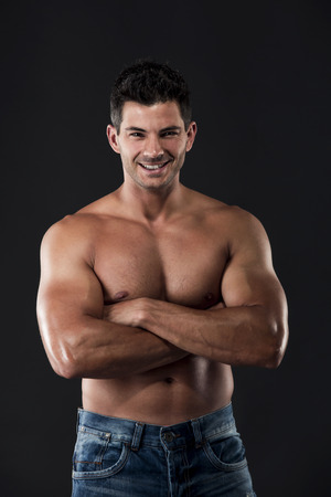 Portrait of a muscular man posing without a shirt against dark backgroundの写真素材