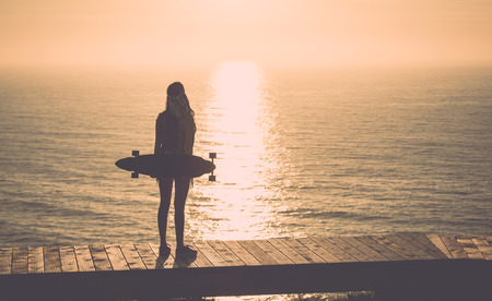 Beautiful and fashion young woman posing with a skateboard