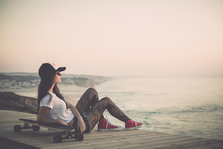 Beautiful and fashion young woman posing with a skateboard