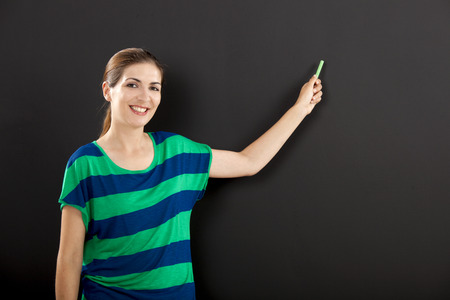 Happy woman writing on  chalkboard, with copy space for designerの写真素材